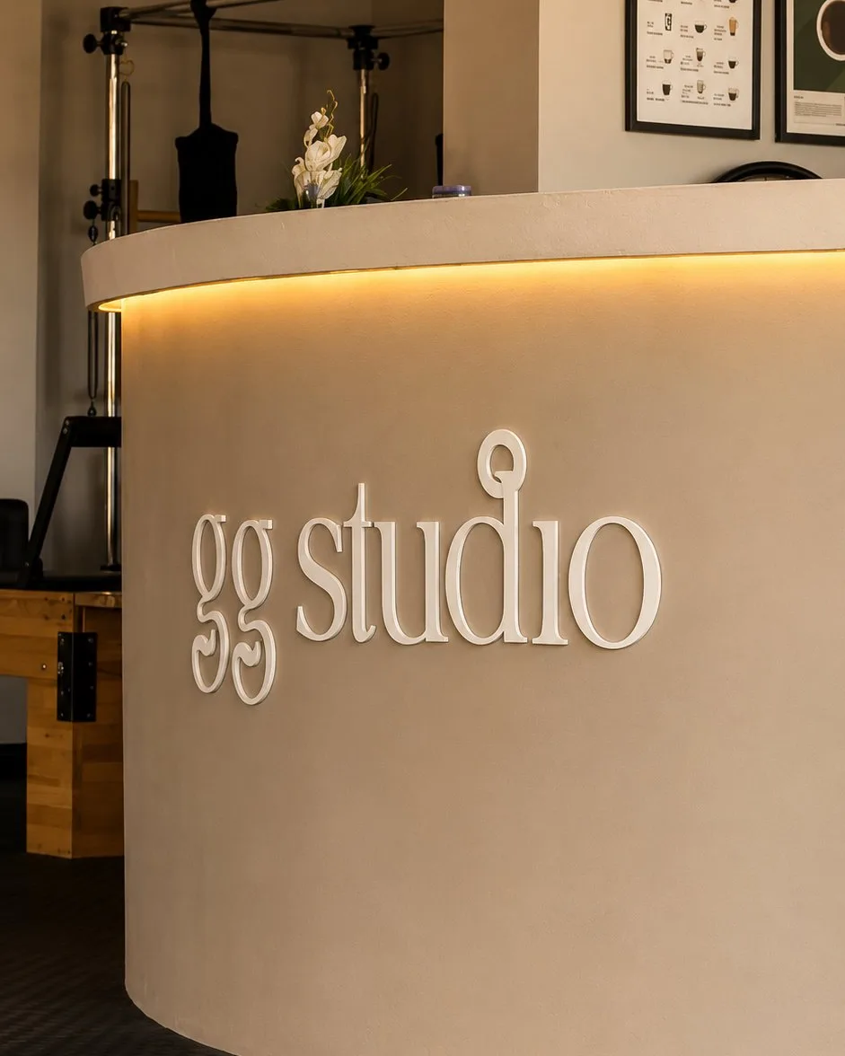 GG Studio logosu — resepsiyon masası üzerinde amber ışıklı yazı